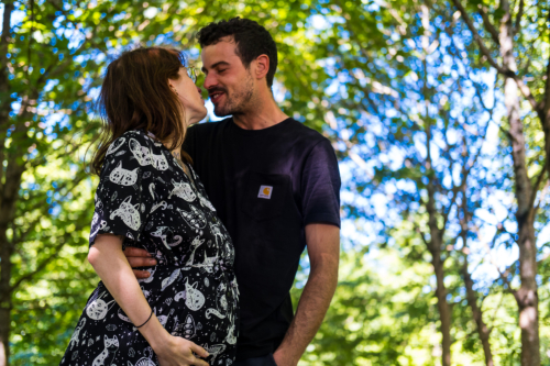 Couple attendant un enfant. Ils se regardent en souriant. Il la tient par la taille