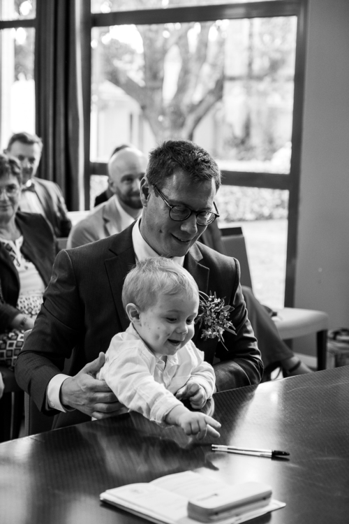 Enfant sur les genoux de son père attrapant le stylo