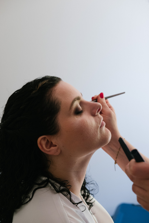 Mariée se faisant maquiller. Elle ferme les yeux pendant qu'on lui applique un fard à paupière