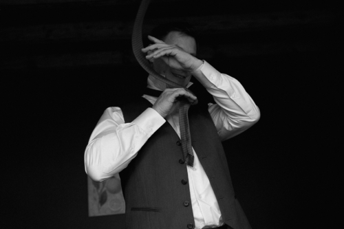 Marié en train de nouer sa cravate pour la cérémonie. La photo montre la cravate volant autour de sa tête