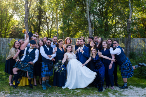 Photo de groupe pendant un mariage en Occitanie sur le thème Festival bleu et or. Les participants font des grimaces